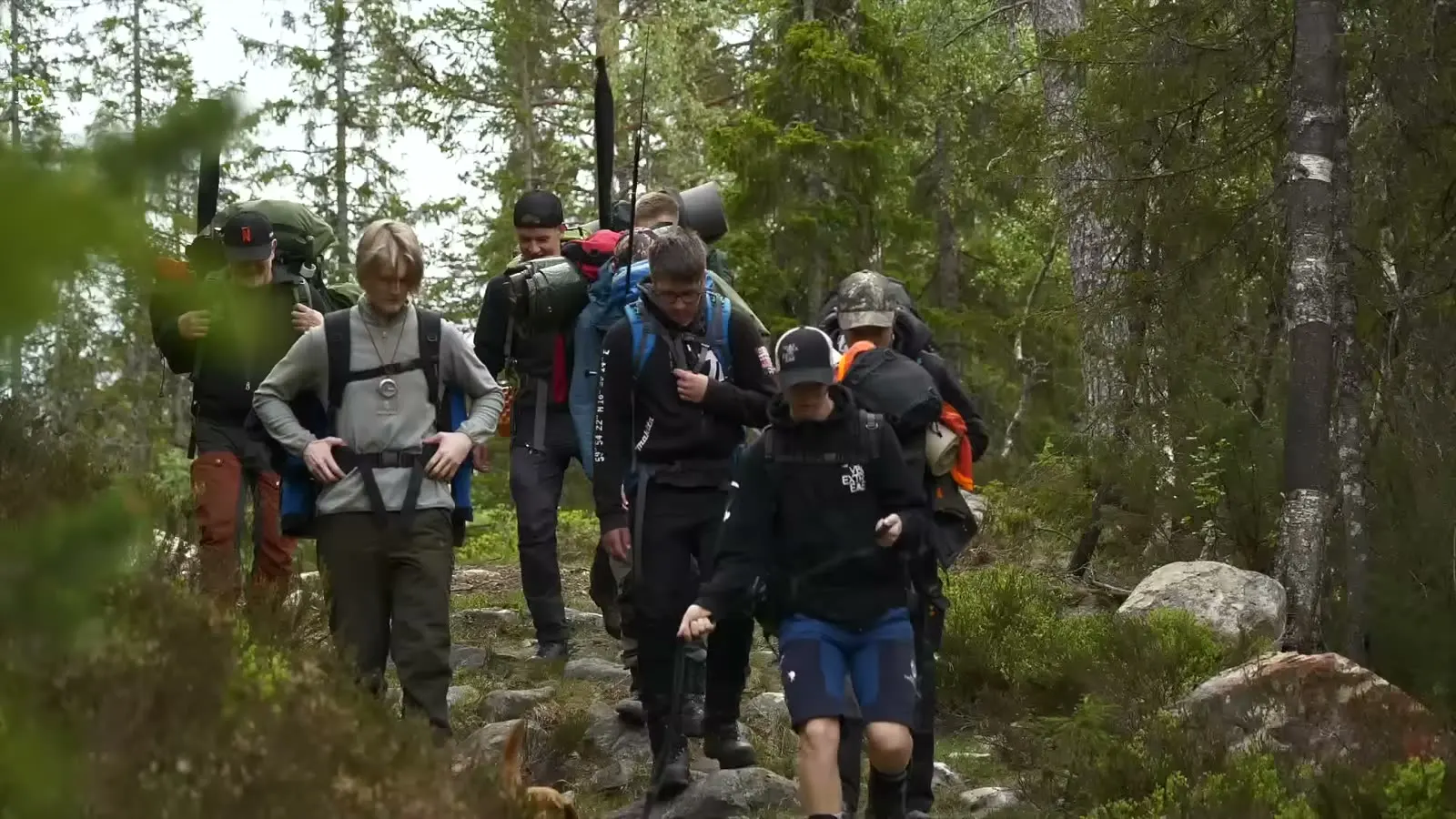 Elever med fullpakkede sekker på tur i skogen